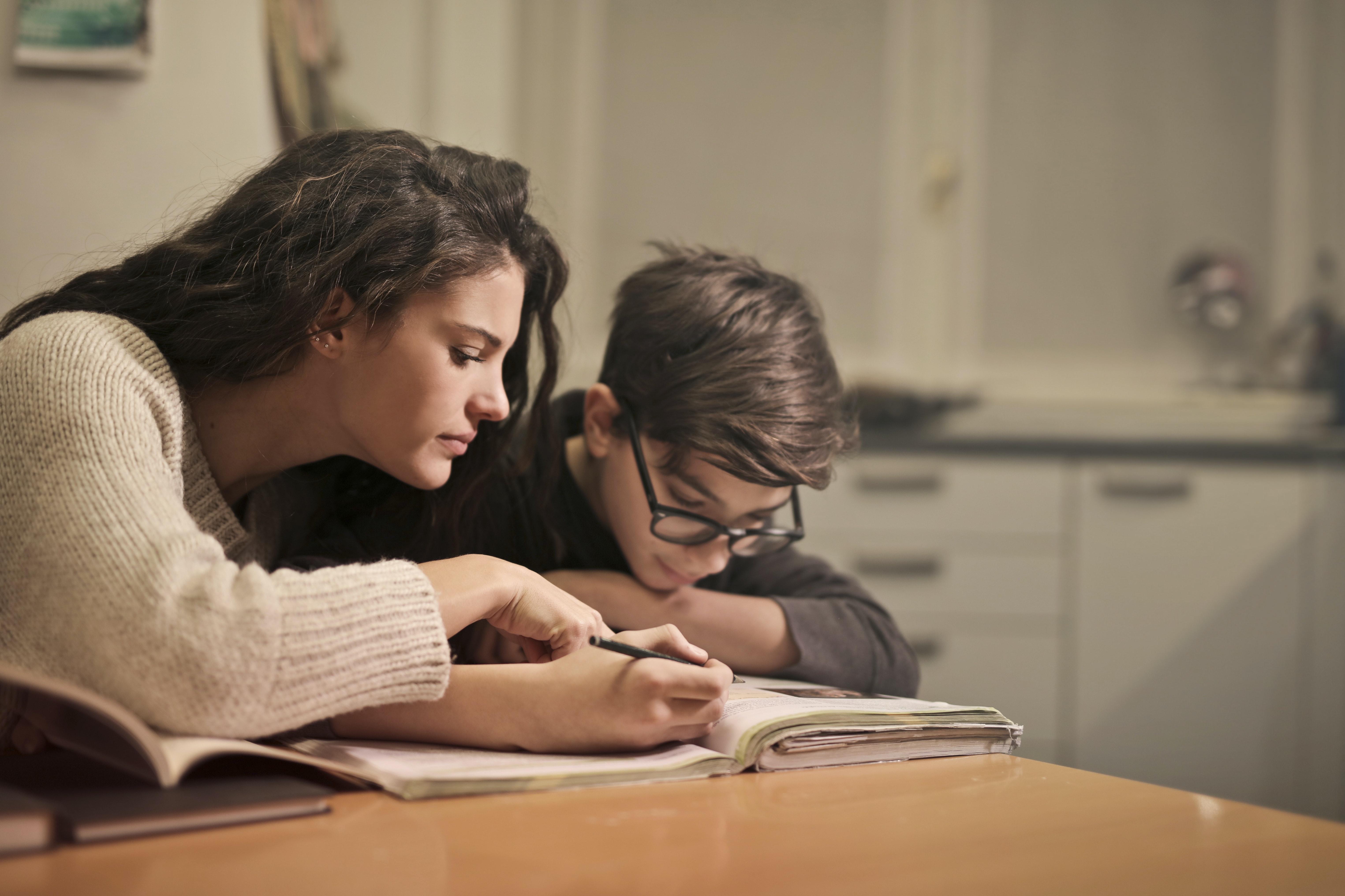 Jongen die wordt geholpen bij huiswerk door een mevrouw